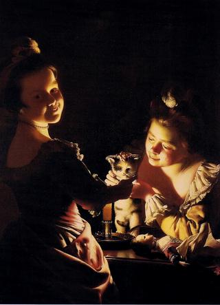 两个女孩在烛光下给小猫穿衣服