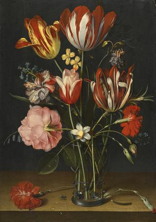 Still life of tulips, carnations, a rose and other flowers in a glass beaker  on a wooded ledge